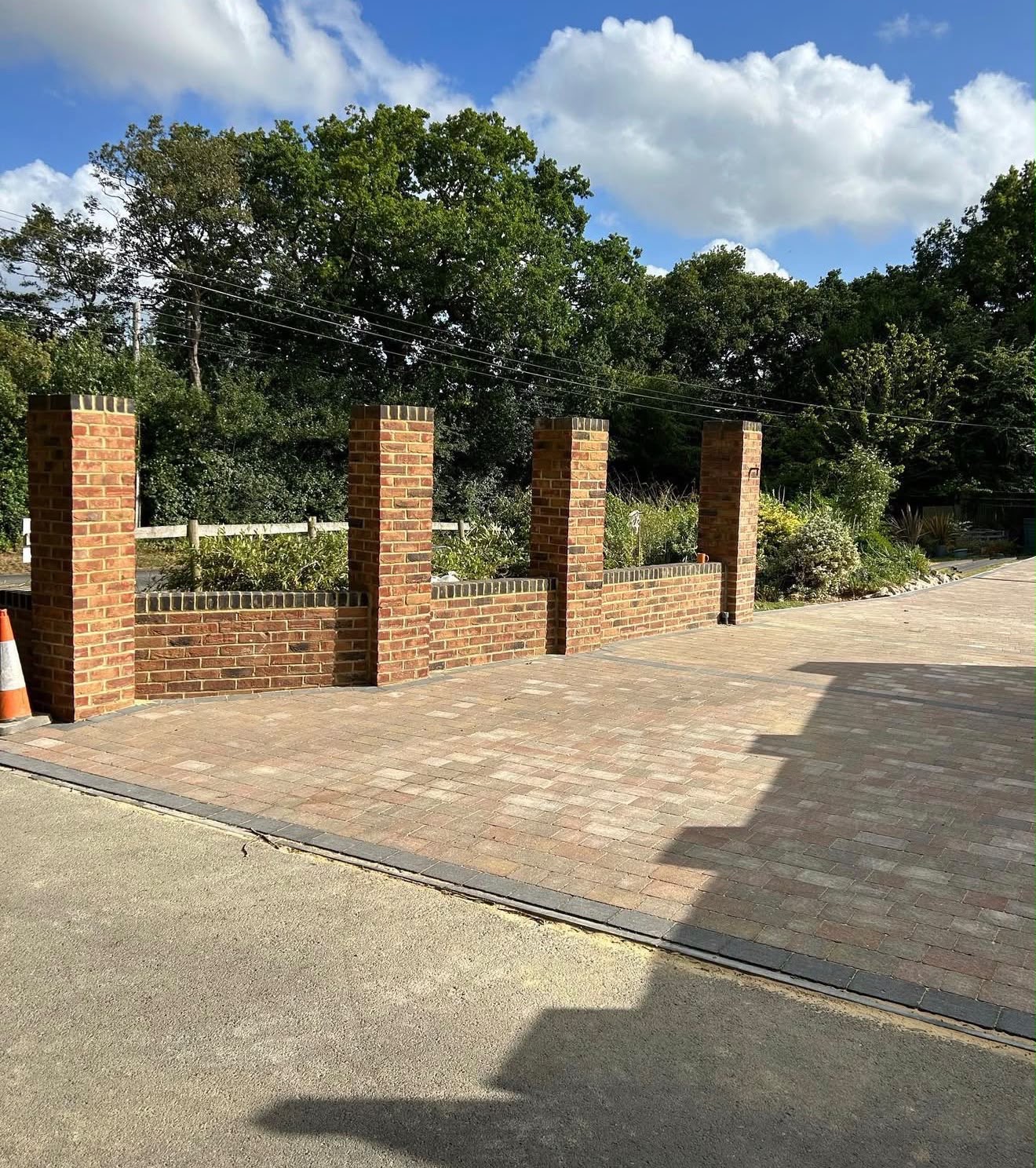 Block paving driveway with brick pillar entrance and planters