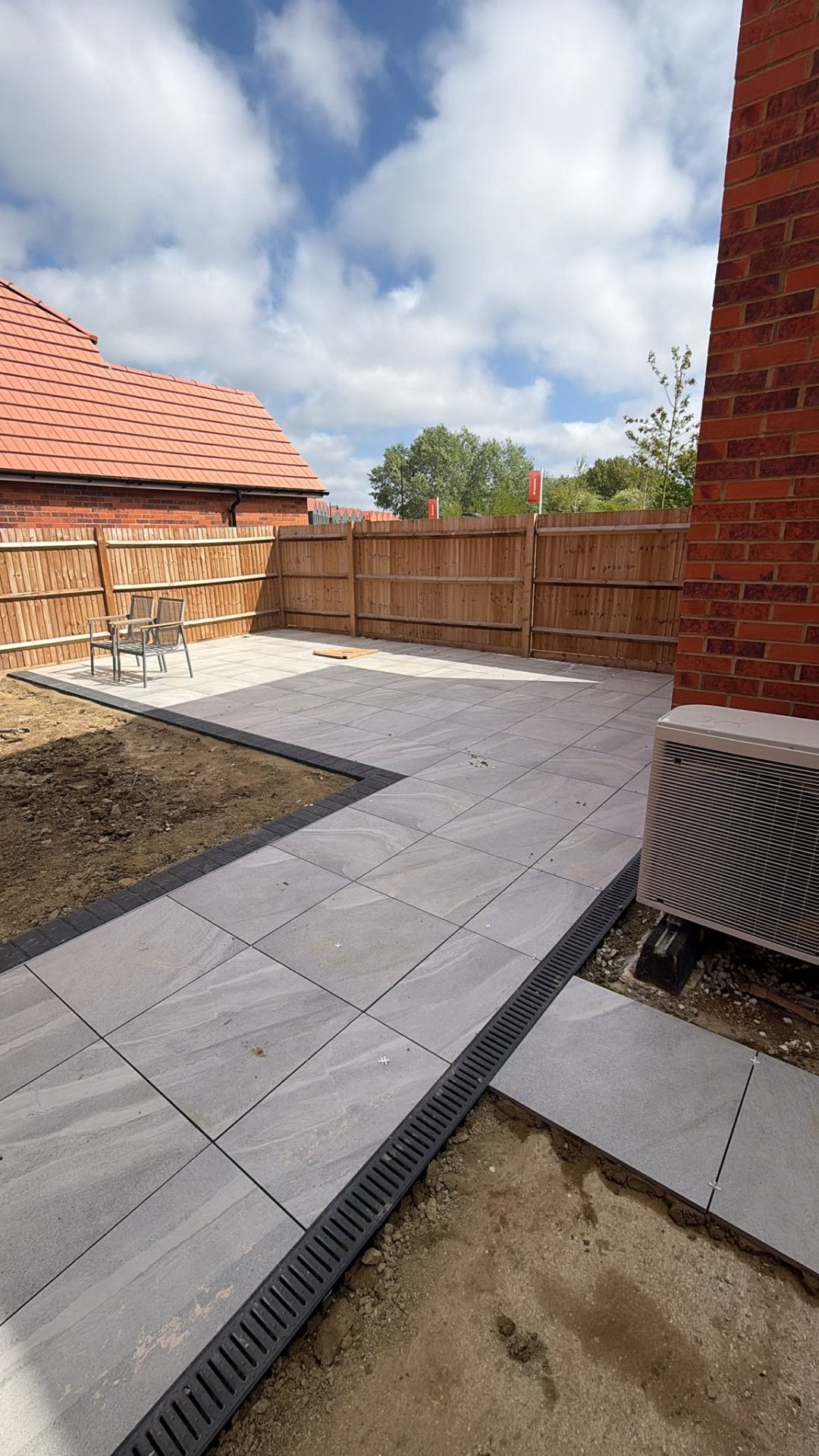 Grey porcelain patio with charcoal block border at a new build home