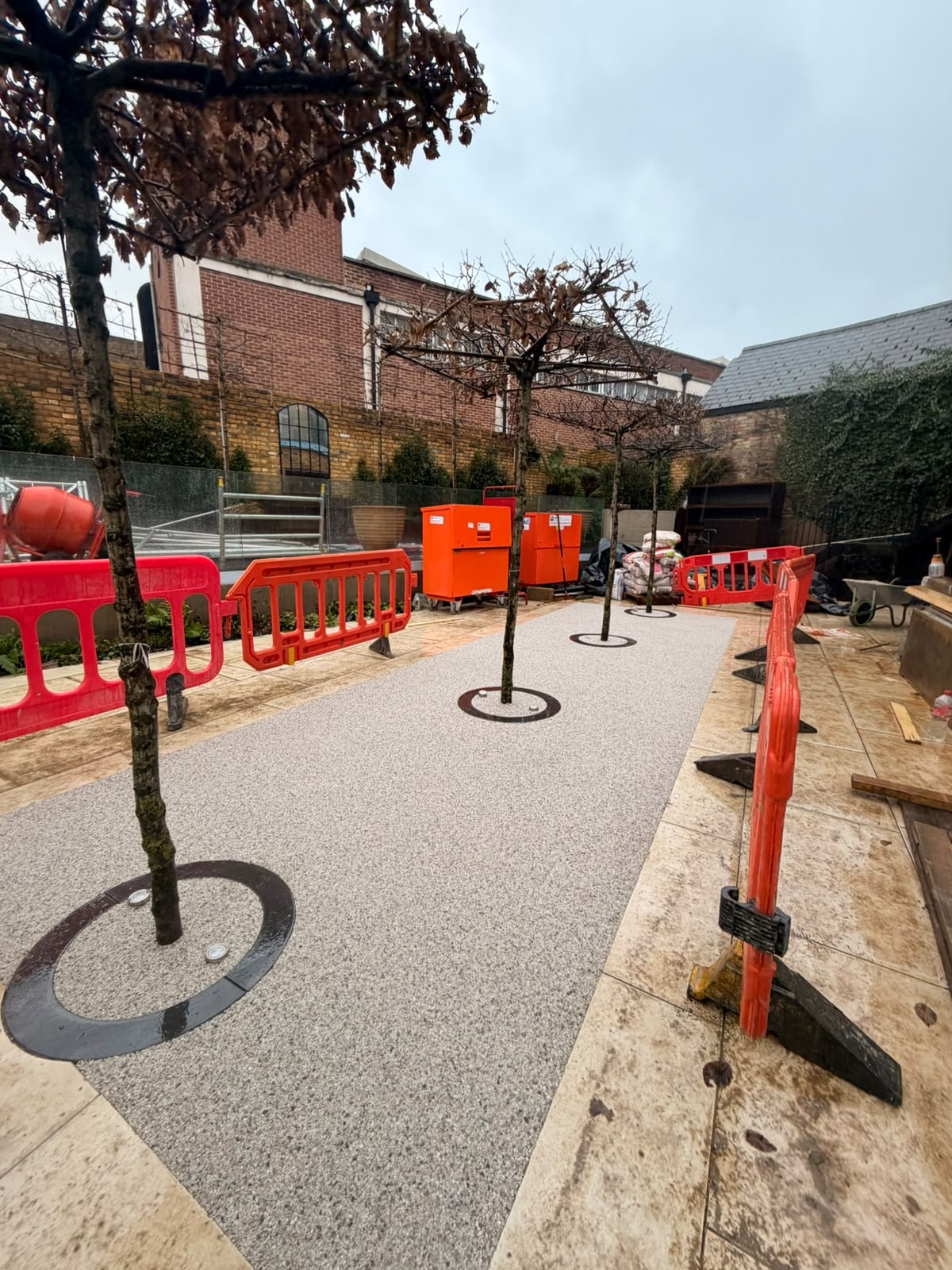 Silver resin bound courtyard with tree surrounds in a London garden