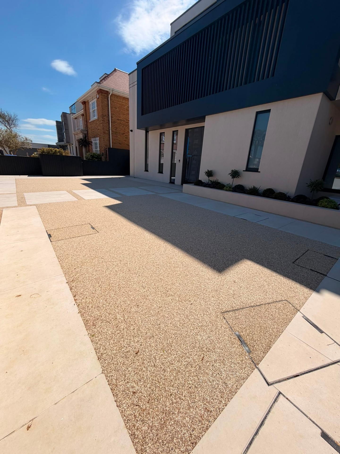 Gold resin bound driveway with sandstone paving borders