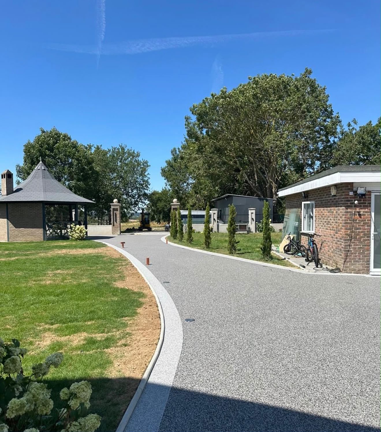 Sweeping silver resin bound private drive with landscaped lawn