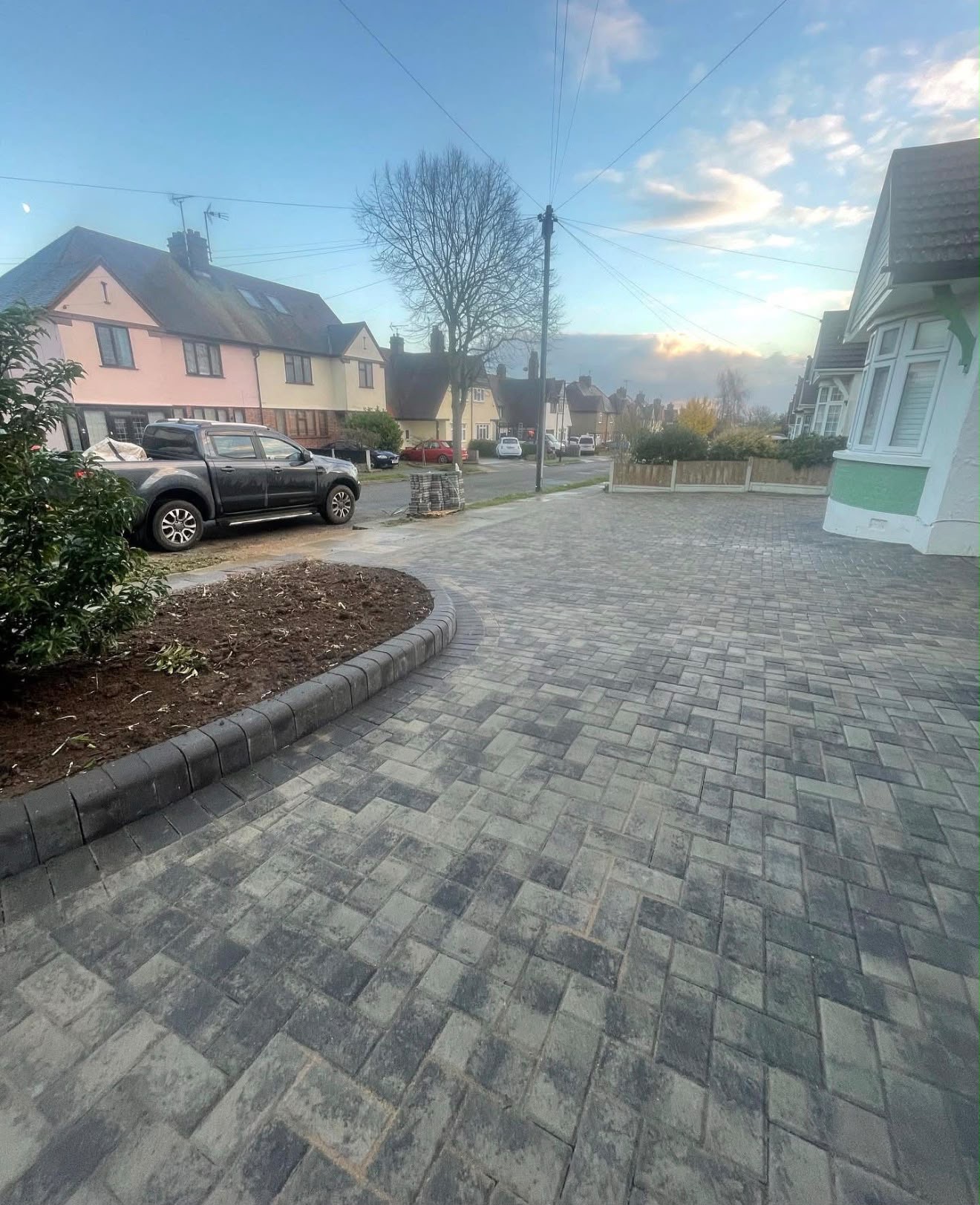 Charcoal block paving driveway with curved border planter