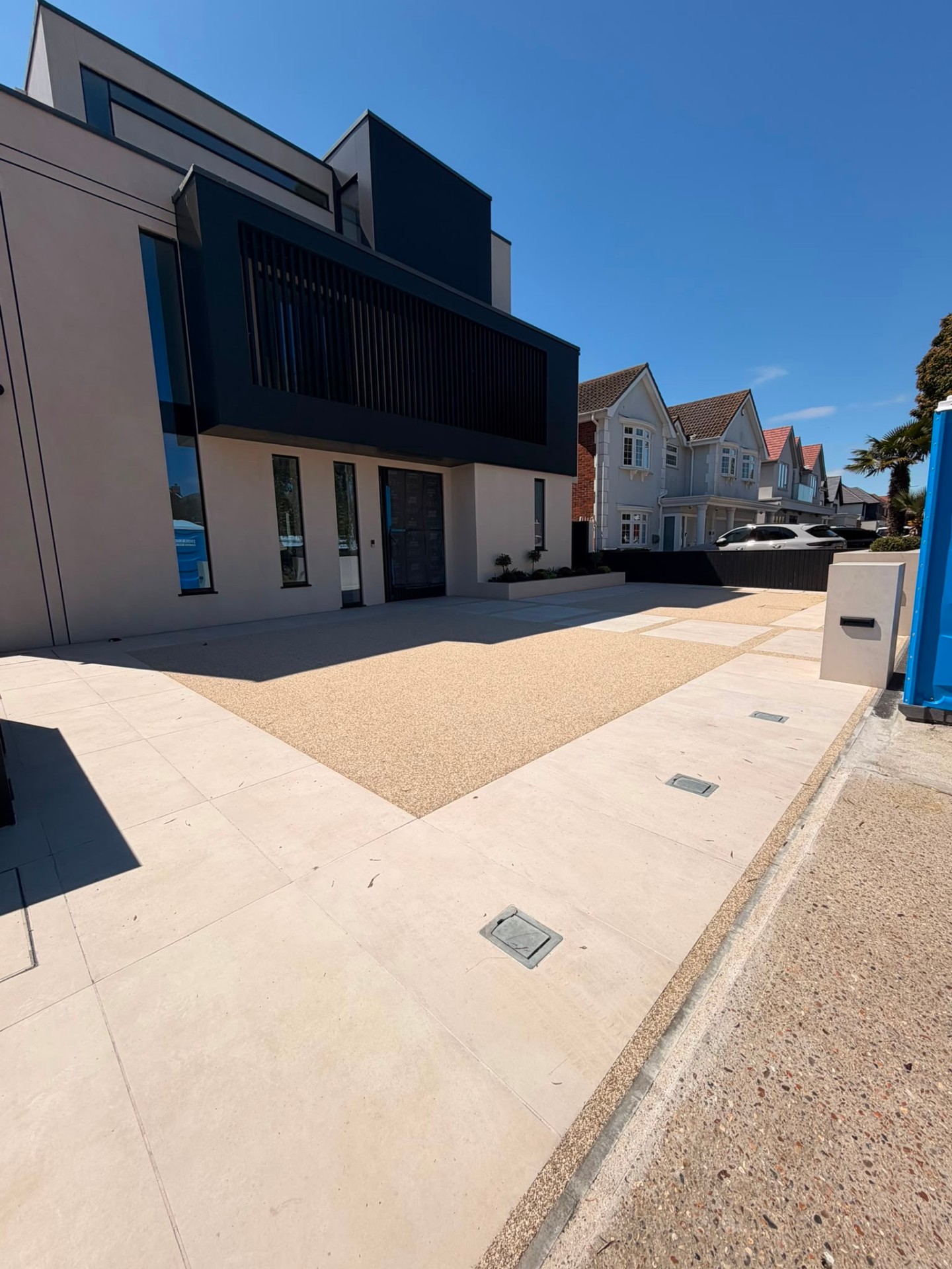 Gold resin bound driveway with porcelain paving detail at a contemporary home