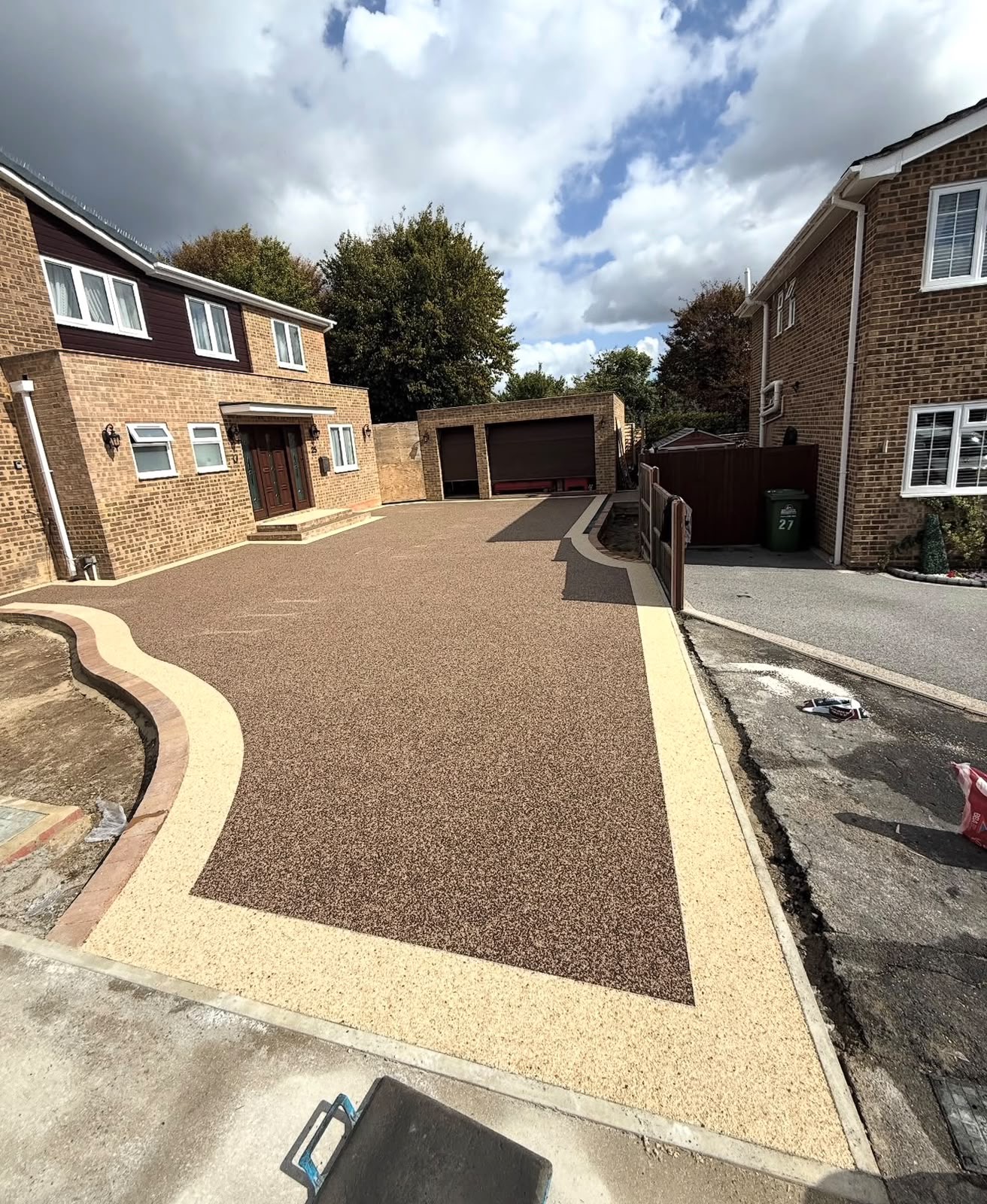 Brown resin bound driveway with contrasting gold border at a family home